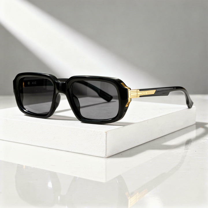 Black sunglasses with gold accents on a white surface